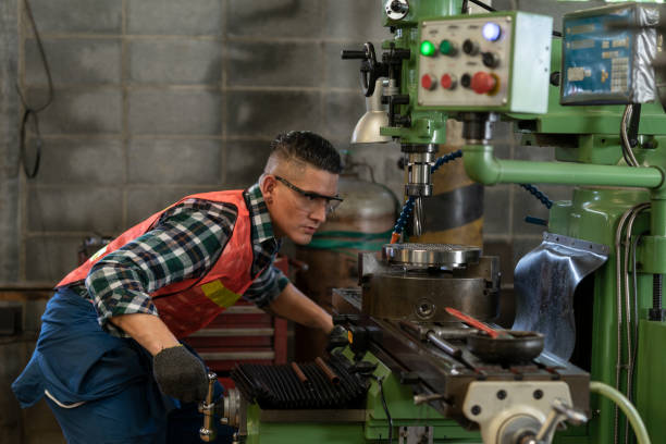 A man in a vest and safety goggles operating a machine